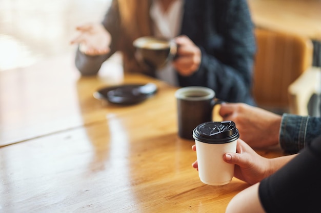 Imagem de close de pessoas conversando e bebendo café juntas em uma cafeteria