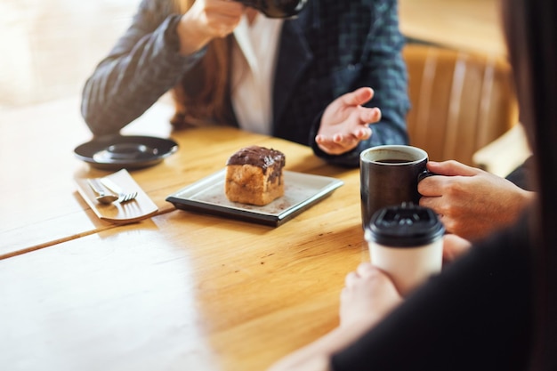 Imagem de close de pessoas conversando e bebendo café juntas em uma cafeteria