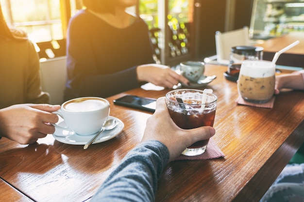Imagem de close de pessoas tomando café juntas em um café