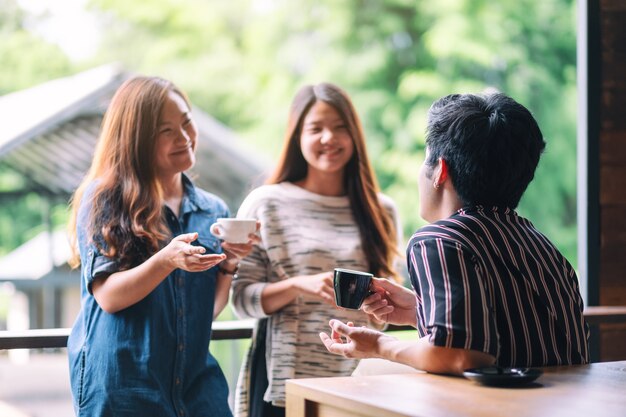 Imagem de close de três pessoas conversando e bebendo café juntas em uma cafeteria