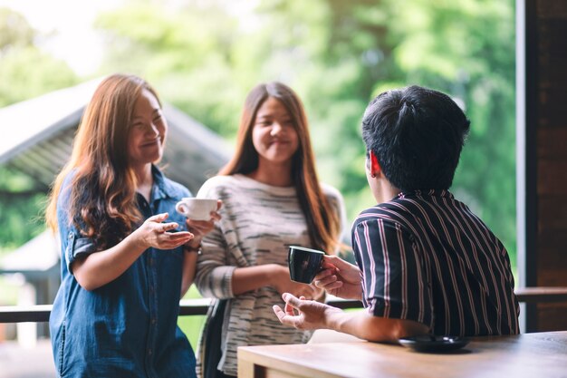 Imagem de close de três pessoas conversando e bebendo café juntas em uma cafeteria