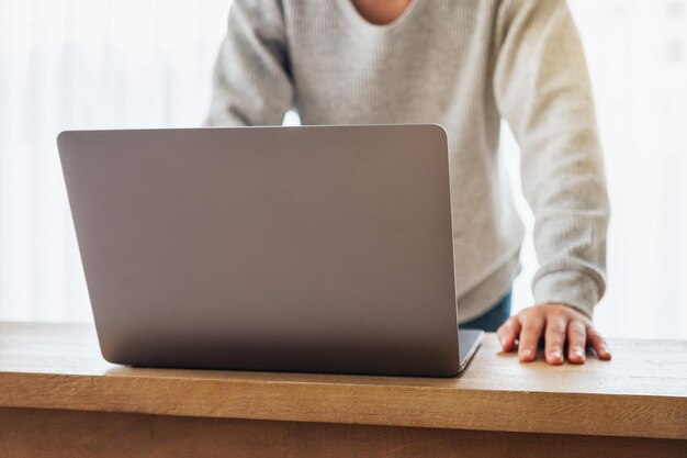 Imagem de close de um empresário trabalhando e usando um laptop em uma mesa de madeira