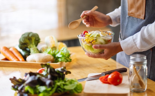 Imagem de close de uma chef feminina cozinhando e segurando uma tigela de salada de legumes frescos para comer na cozinha