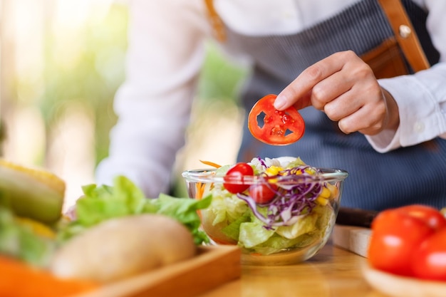 Imagem de close de uma chef feminina cozinhando uma salada de vegetais frescos na cozinha