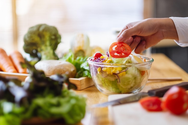 Imagem de close de uma chef feminina cozinhando uma salada de vegetais frescos na cozinha