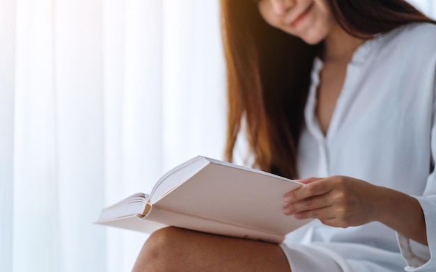 Imagem de close de uma linda mulher asiática lendo um livro em um quarto em casa