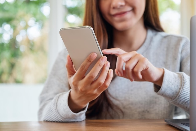 Imagem de close de uma linda mulher asiática segurando e usando um telefone celular