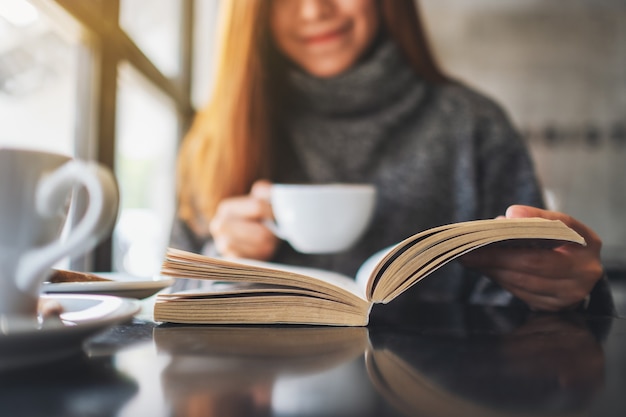 Imagem de close de uma linda mulher lendo um livro enquanto toma café pela manhã