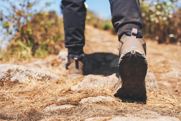 Imagem de close de uma mulher caminhando com botas de trekking no topo de uma montanha