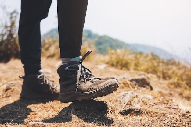 Imagem de close de uma mulher caminhando com botas de trekking no topo de uma montanha