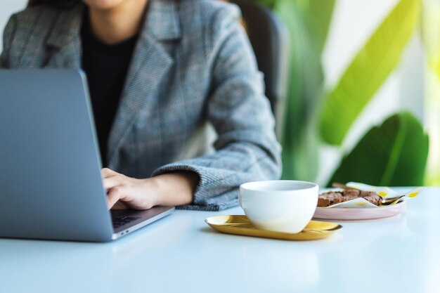 Imagem de close de uma mulher de negócios usando e trabalhando em um laptop no escritório