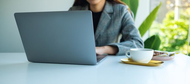 Imagem de close de uma mulher de negócios usando e trabalhando em um laptop no escritório