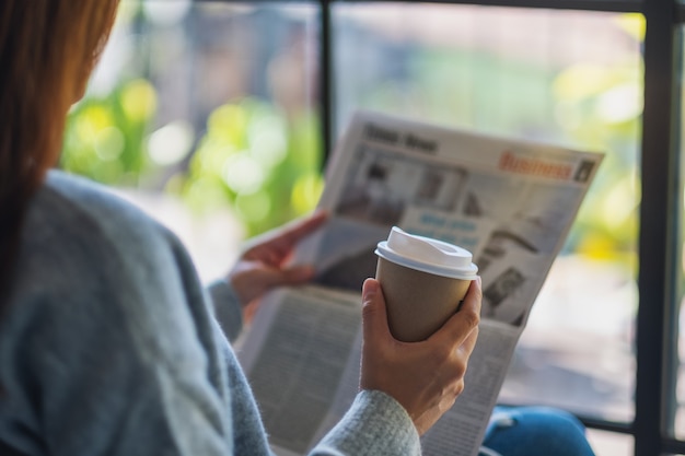 Imagem de close de uma mulher lendo jornal e tomando café pela manhã