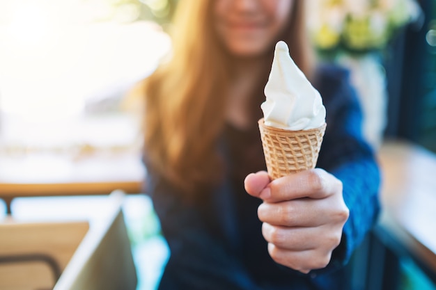 Imagem de close de uma mulher segurando e mostrando uma casquinha de waffle de sorvete