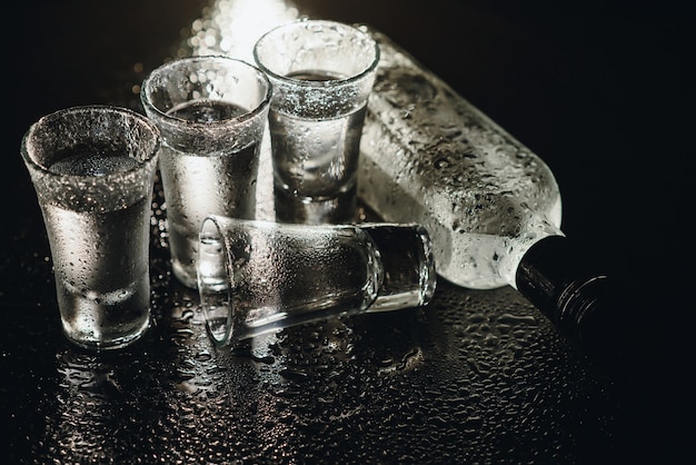 Imagem de close-up de garrafa e copos de vodka isolados no preto