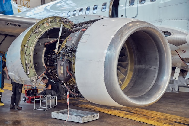 Imagem de close-up de grande turbina aberta com asa na modernização programada de avião de passageiros no aeródromo