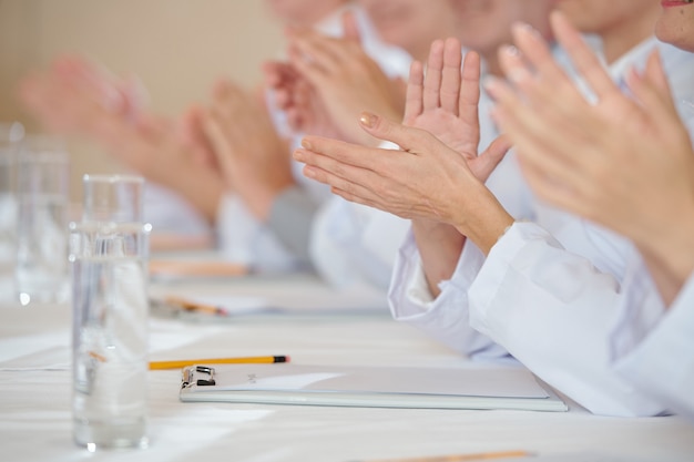 Foto imagem de close-up de profissionais da área médica batendo palmas após o discurso de um colega na conferência