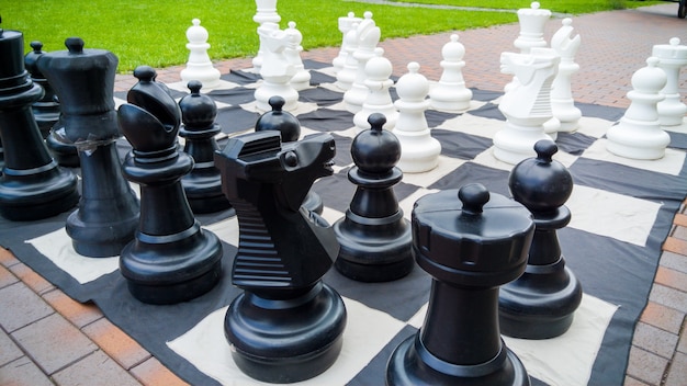 Imagem de close up do tabuleiro de xadrez gigante e figuras de xadrez no parque. Entretenimento e diversão para a família ao ar livre