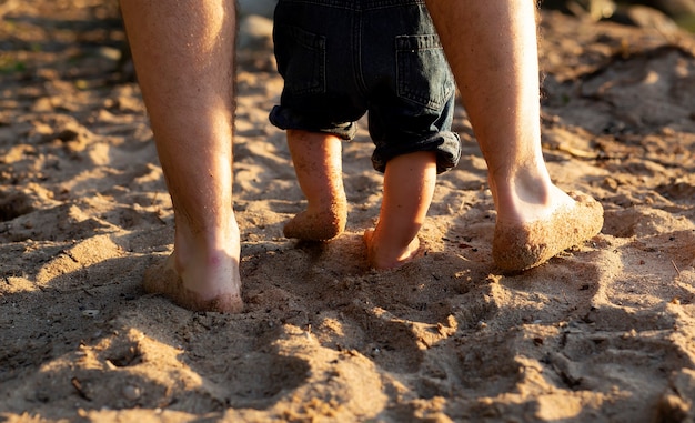 Imagem de close-up pernas de pai e filho caminhando à beira-mar