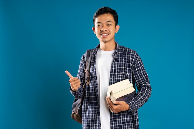 Imagem de conteúdo do estudante do sexo masculino sorrindo enquanto aponta com o polegar isolado no fundo azul