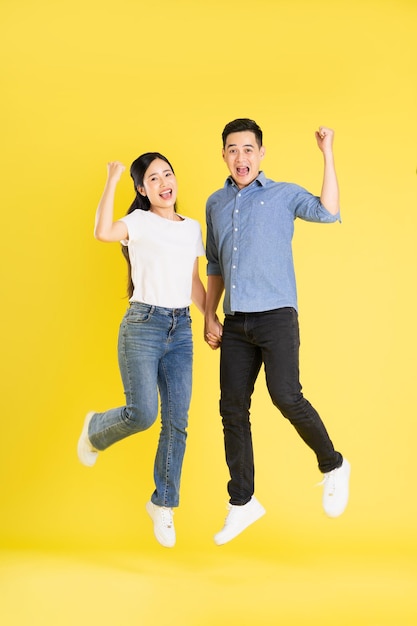 Imagem de corpo inteiro de casal asiático posando em fundo amarelo