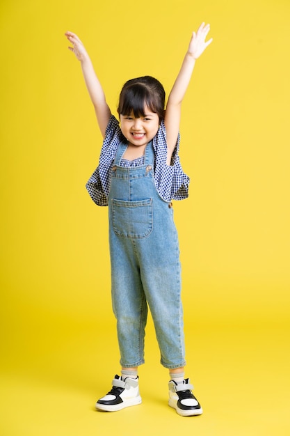 Imagem de corpo inteiro de linda menina asiática em fundo amarelo