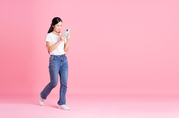 Imagem de corpo inteiro de menina asiática posando em fundo rosa