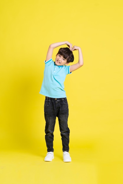 Imagem de corpo inteiro de menino asiático posando em fundo amarelo