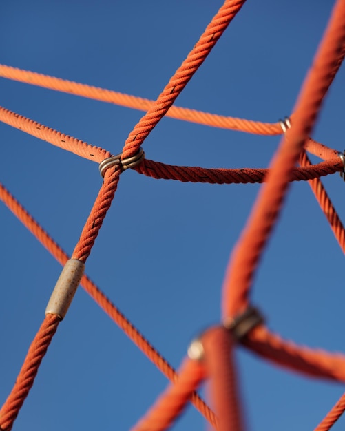 Imagem de detalhe abstrata de estrutura de escalada com cordas vermelhas e céu azul no playground