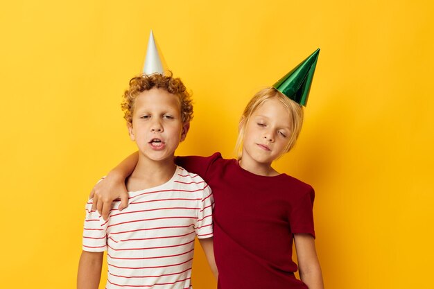 Imagem de diversão positiva de férias de menino e menina com tampas em seu fundo isolado de cabeça