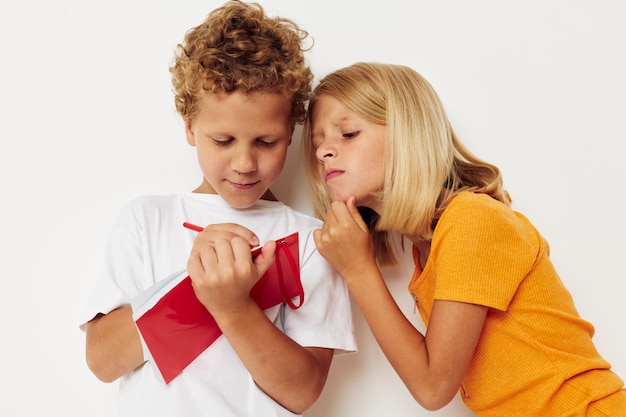 Imagem de diversão positiva de menino e menina em camisetas coloridas com um fundo isolado do bloco de notas inalterado