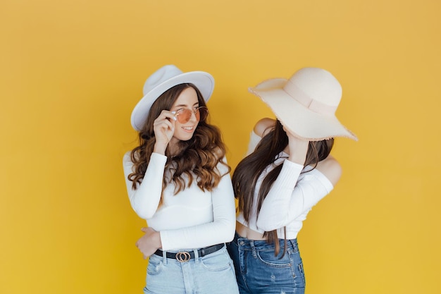 Imagem de duas garotas apontando e desviando o olhar sobre amarelo