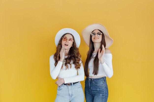 Imagem de duas garotas apontando e desviando o olhar sobre amarelo