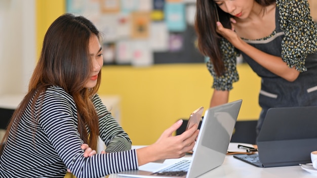 Foto imagem de duas universitárias trabalhando juntas em uma cafeteria, laptop e tablet na mesa