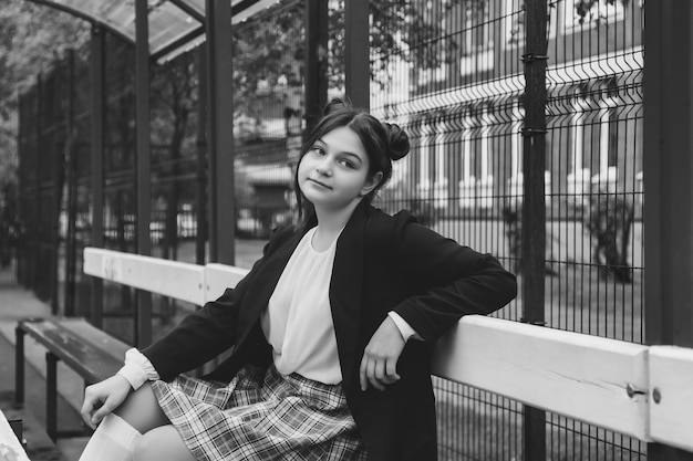 Imagem de estilo de filme de ruído de arte. retrato de uma colegial de  treze anos de blusa branca, saia xadrez e jaqueta na escola. menina  adolescente emocional posando olhando para a