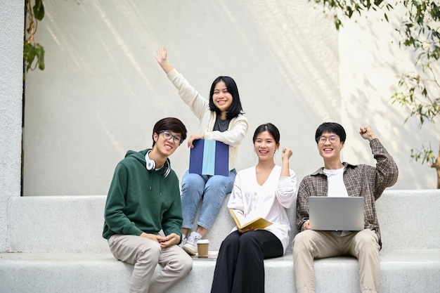 Imagem de estudantes universitários felizes sentados juntos em um banco em uma área de relaxamento do campus