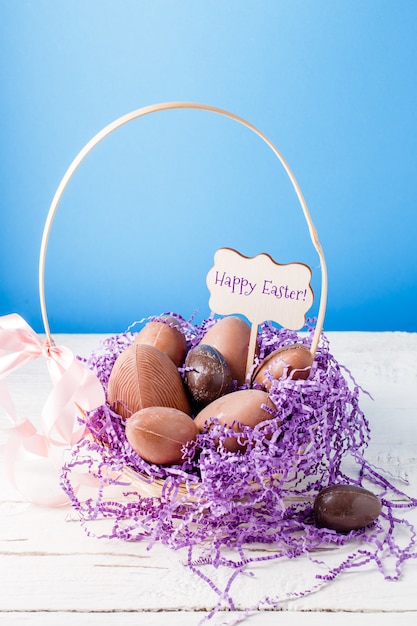 Imagem de frango, ovos de chocolate, papel decorativo roxo na cesta, desejo feliz Páscoa