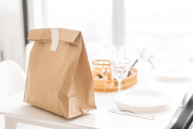 Imagem de fundo do saco de papel artesanal na mesa de madeira no interior da cozinha branca com rótulo de alimentos orgânicos, serviço de entrega de alimentos, espaço de cópia.