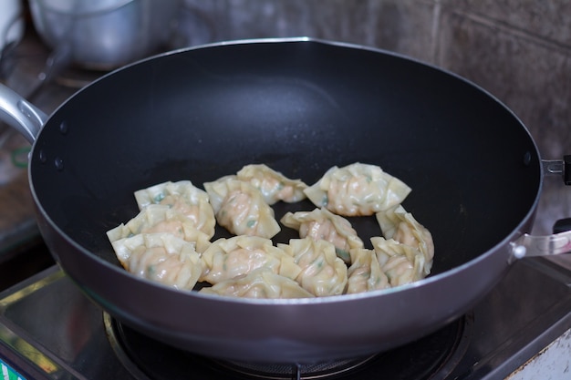 Imagem de Gyozas de bolinhos fritos com carne de porco sendo cozida em uma panela