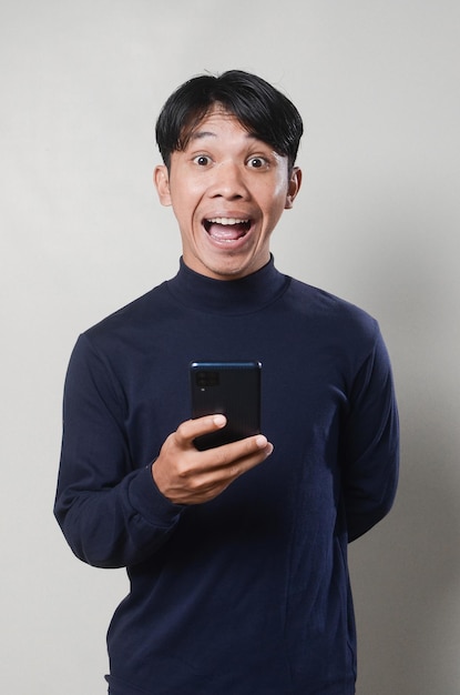 Imagem de homem asiático alegre sorrindo e usando telefone celular