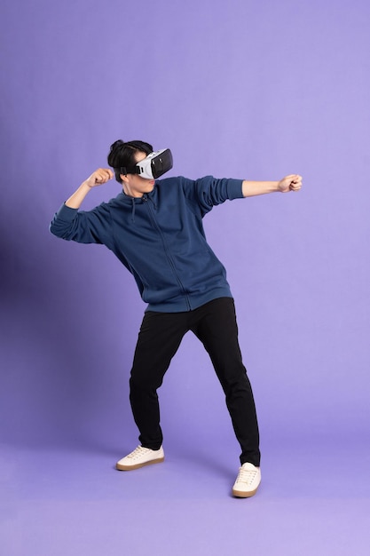 Imagem de homem asiático usando óculos de realidade virtual em fundo roxo