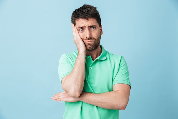 Imagem de homem barbudo bonito jovem entediado cansado posando isolado sobre uma parede azul.