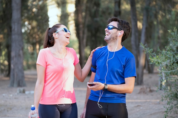 Imagem de homem e mulher excitados com fones de ouvido, ouvindo música em telefones celulares no parque