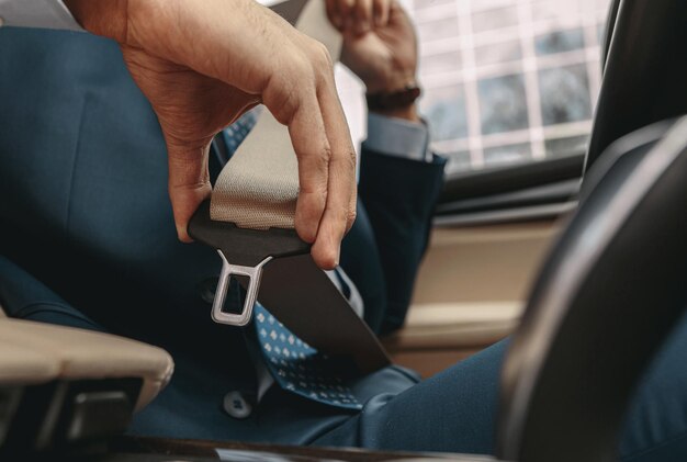 Imagem de homem sentado atrás do volante de seu carro e apertando o cinto de segurança