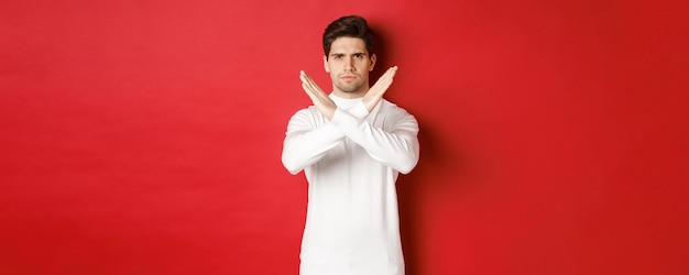 Imagem de homem sério e zangado em suéter branco expressa desaprovação storng mostrando sinal de cruz para sto ...