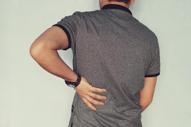 Foto imagem de homem sofrendo dor nas costas contra fundo azul paciente com insuficiência renal segura a mão atrás das costas artrose condrose osteoporose músculo e dor nas articulações