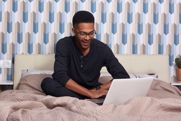 Imagem de homem sorridente feliz sentado em sua cama