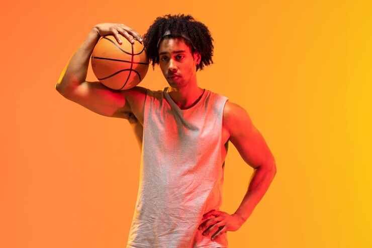 Foto imagem de jogador de basquete birracial com basquete em fundo laranja a amarelo. conceito de esportes e competição.