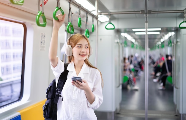 Imagem de jovem asiática usando smartphone no metrô