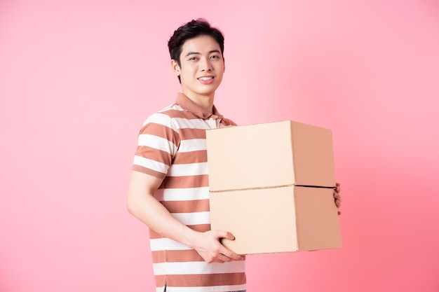 Imagem de jovem asiático segurando papelão no fundo rosa